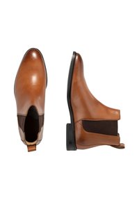 Chelsea-stövlar i brunt läder med svarta elastiska sidor och svarta sulor, visade från ovan och sida mot en vit bakgrund.