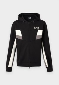 Čierna mikina s kapucňou a zapínaním na zips, s bielymi a sivými pruhmi cez hrudník a rukávy, s logom EA7 Emporio Armani na ľavej strane hrudníka.