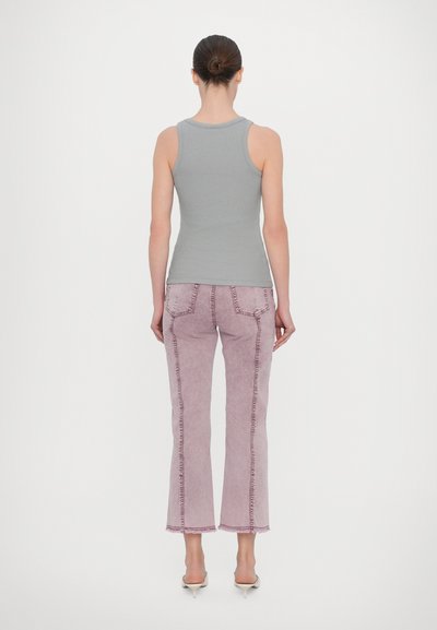 Graues geripptes Tanktop kombiniert mit blassen rosa weit geschnittenen Jeans mit fransigen Säumen und kontrastierenden Nähten. Modell trägt Slip-On-Absätze.