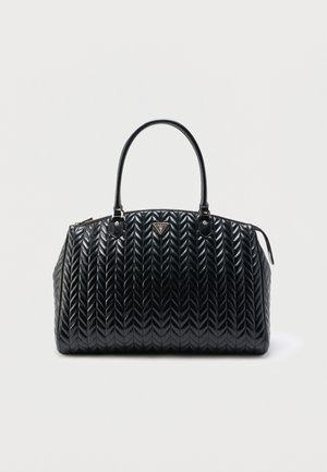 Μαύρη καπιτονέ δερμάτινη τσάντα με διπλές λαβές και χρυσό τριγωνικό λογότυπο Guess στο κέντρο μπροστά.