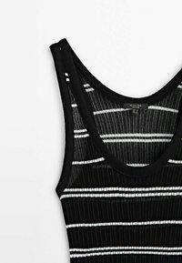 Débardeur noir côtelé avec des rayures horizontales blanches, un col arrondi et des bretelles épaisses. La texture est douce et extensible.