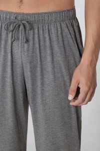 Graue Loungehosen mit elastischem Bund und Kordelzug. Weicher, leichter Stoff mit einer dezenten Textur. Hand ruht an der Seite.