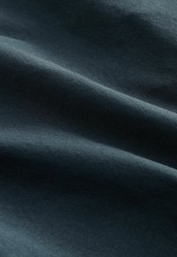 Dunkelblauer Stoff mit glatter Textur, der sanfte Drapierungen und einen subtilen Glanz zeigt, mit feinen Webarten und ohne sichtbare Muster.