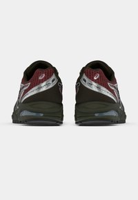 Fekete és piros hálós anyagú sportcipők ezüst részletekkel, ívelt sarokkal és texturált talppal a jobb tapadás érdekében.