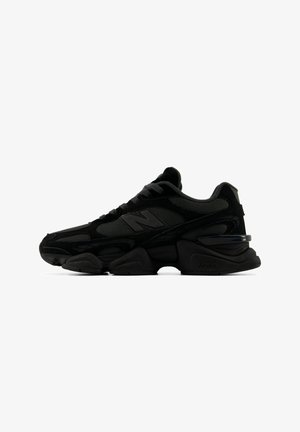 Baskets de sport noires New Balance avec tige en mesh et daim, semelle épaisse sculptée, et logo "N" sur le côté, présentées de profil sur fond blanc.