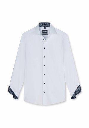 Chemise blanche à manches longues avec boutons noirs et motifs floraux foncés à l’intérieur du col et des poignets, présentée avec les manches partiellement retroussées.