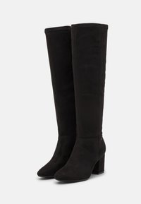 Botas negras hasta la rodilla, hechas de suave ante, con punta afilada y un tacón cuadrado grueso, con un detalle de costura mínimo y sin herrajes visibles.