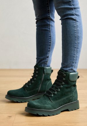 Green suede ankle boots with a rugged sole, lace-up front, and padded collar. Textured finish and side zipper for easy wear.