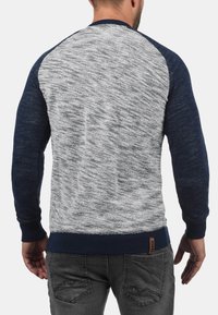 Grå og marineblå fargeblokkert genser med teksturert strikkedesign og ribbet mansjetter. Synlig merkevaremerke på den nederste delen av ryggen.