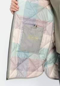 Das Innere der gesteppte Jacke zeigt ein pastellfarbenes Karomuster in Blau, Rosa und Grau. Sie verfügt über eine wasserabweisende, winddichte Tasche mit Symbolen.