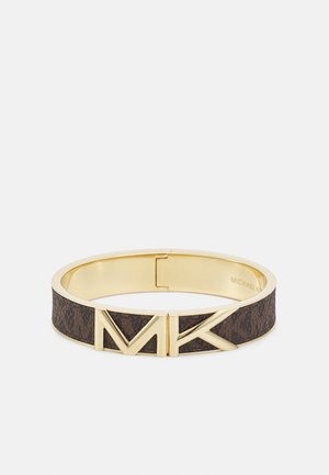Bracelet doré et marron avec bande texturée et grande fermeture logo MK doré, forme circulaire, accessoire de mode de luxe.