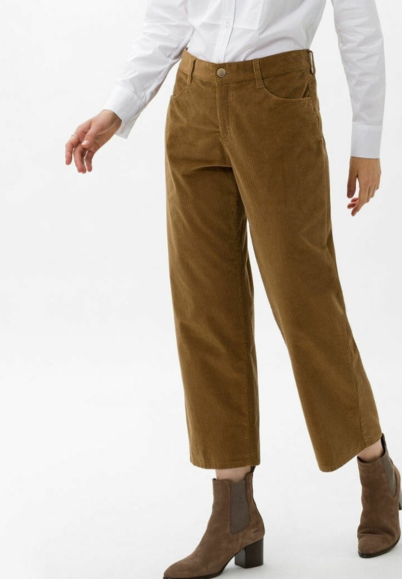 Brązowe szerokie spodnie corduroy z wysokim stanem, z dwoma przednimi kieszeniami i zapięciem na guzik, w połączeniu z brązowymi zamszowymi botkami do kostek.