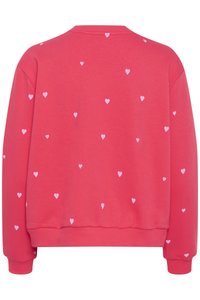 Rózsaszín pulóver kerek nyakkal és hosszú ujjal, kicsi fehér szív mintákkal díszítve, melyek egyenletesen elosztva találhatók rajta.