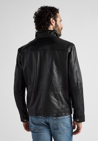 Schwarze Lederjacke mit hohem Kragen, paneeliertem Design und strukturierten Ärmeln. Ausgestattet mit Druckknöpfen und einer glatten Oberfläche.
