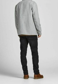 Szary żakiet z wełny o prostym kroju, w połączeniu z czarnymi jeansami o slim fit i brązowymi skórzanymi butami. Prosty design, bez widocznych wzorów.