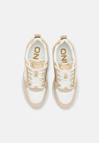 Beige and white sneakers with metallic gold accents, textured panels, and contrasting laces. Features the brand "ONLY" on the tongue.