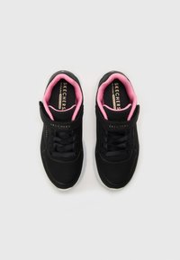 Baskets de sport noires avec un dessus texturé, doublure intérieure rose et sangle Velcro. Présente des perforations pour la respirabilité et une semelle rembourrée.