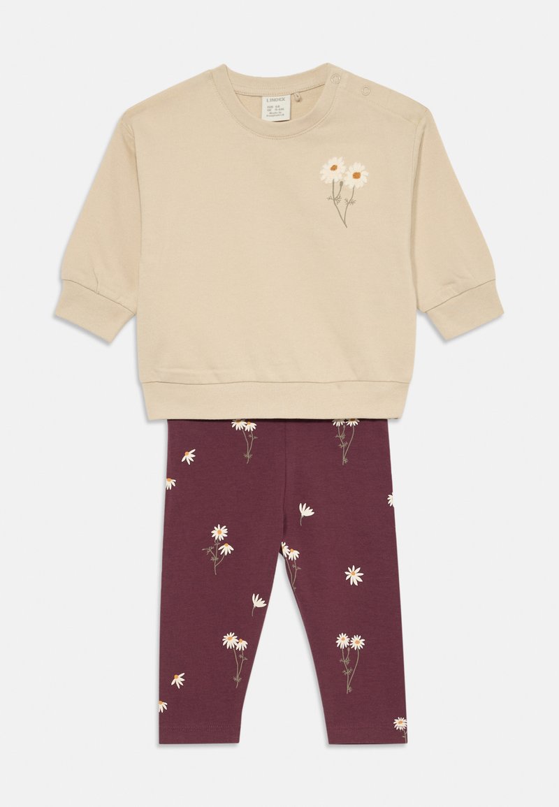 Beiger Pullover mit floraler Stickerei und Druckknöpfen, kombiniert mit burgunderfarbenen Leggings mit einem weißen Gänseblümchenmuster. Weiches Baumwollmaterial.