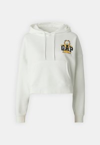 Sudadera blanca recortada hecha de un tejido suave, con un bolsillo frontal y un gráfico de Garfield con la palabra "GAP" en letras negras.