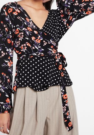 Blusa nera avvolgente con motivo floreale in rosso e viola, con orlo peplum a pois e maniche lunghe con dettaglio a lacci in vita.