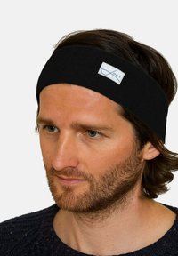 Black fabric headband featuring a rectangular white label with blue text. It has a smooth texture and a simple, elongated design.