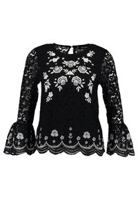 Svart spetsblus med långa ärmar och vit blommig broderi, vågig nederkant och utsvängda manschetter, med en nyckelhålsknäppning bak.