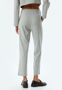 Pantalones grises a medida con una textura suave, que presentan una cintura de altura media, bolsillos de costura lateral y un largo recortado.