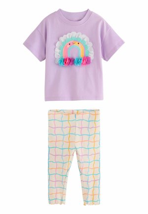 Lilla kortærmet skjorte med en smilende regnbue og stofblomster kombineret med cremefarvede leggings med farverige bølgede gitterlinjer.