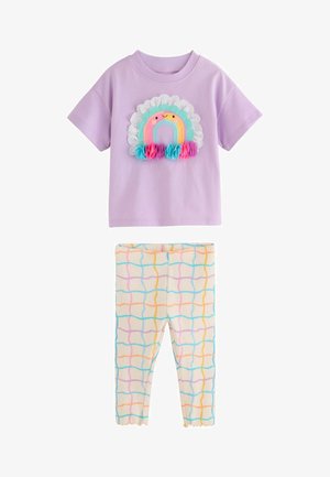 Ibolya rövid ujjú ing mosolygó szivárvánnyal és szövetvirágokkal, krém színű leggingssel, színes hullámos rácsvonalakkal.