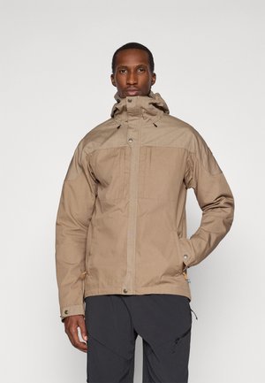 Beige wasserdichte Jacke mit hohem Kragen, Kapuze und Reißverschluss vorne. Sie hat ein zweifarbiges Design, große Taschen und verstellbare Kordelzüge.