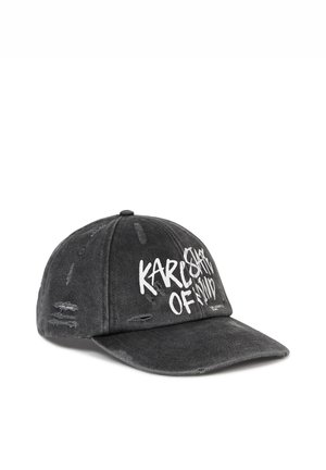 Opotrebovaná čierna baseballová čiapka s bielym graffiti štýlom textu "Karl Star of Mind" a zámerne poškodenými trhlinami vpredu a po stranách.