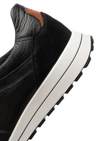 Black leather and suede sneaker heel with brown accent and white rubber sole with treaded black outsole.