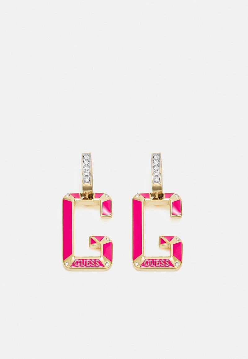 Boucles d'oreilles dorées en forme de lettre G avec émail rose, strass sur le cercle et "GUESS" gravé en bas.