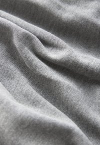 Tissu gris à la texture douce, présentant de légères variations de teinte et une apparence lisse, légèrement extensible. Aucun motif ni accent visible.