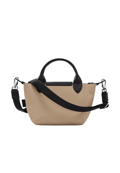 Beige fabric handbag with black leather accents, dual handles, and an adjustable strap. Rectangular shape, smooth texture, and zipper closure.