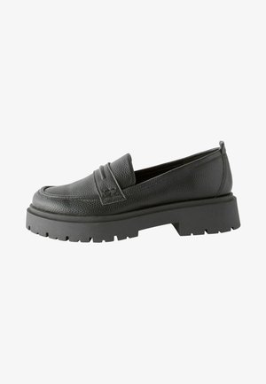 Zwarte leren loafers met een gestructureerde afwerking, opvallende stikdetails en een dikke zwarte rubberen zool met een geprofileerd patroon.
