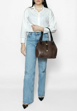 Sac à main texturé marron avec un motif serpent, doté de poignées noires et d'une fermeture à bascule dorée. Jean clair et chemise blanche à boutons.