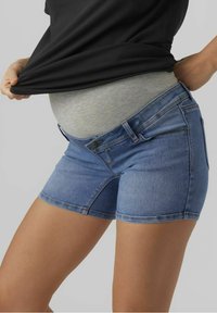 Pantalones cortos de mezclilla en azul claro con un diseño ajustado, que cuentan con una amplia cinturilla elástica gris para mayor comodidad y tejido elástico para facilitar el movimiento.