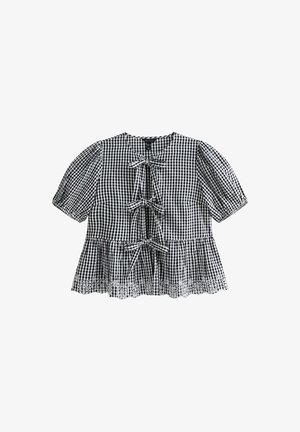 Blusa in gingham bianco e nero con maniche a palloncino corte, tre legature frontali e bordo in pizzo. Tessuto di cotone, vestibilità rilassata.