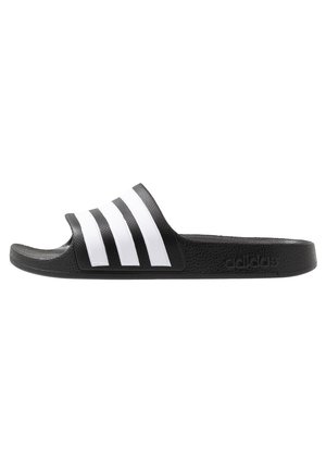 Black slide sandal with a textured strap featuring three white horizontal stripes. The outsole is also black, with a logo embossed on the side.