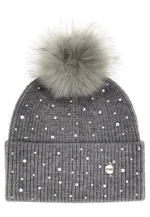 Bonnet en tricot gris avec une texture côtelée, ornée de clous en argent et d'un pompon gris duveteux sur le dessus. Présente une petite étiquette logo "Guess".