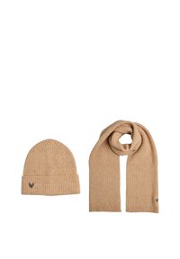 Beige geribbelde gebreide muts en sjaal set, met een smal streepjespatroon en een klein geborduurd logo op elk stuk. Zachte textuur en rekbaar.