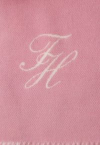Rozā vilnas šal no baltām izšuvumiem ar monogrammu "FH", ar mīkstu, teksturētu apdari un pušķotām malām.