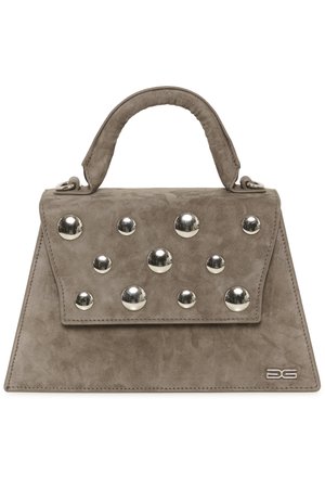 Bolso de ante gris con forma estructurada, que cuenta con un asa superior y tachuelas plateadas en la solapa. Incluye un logo en relieve en el lateral.