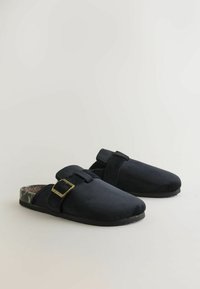 Sorte ruskindssko med en spænde, der har en farverig struktureret indersål og en flad gummisål, designet til nem påklædning.