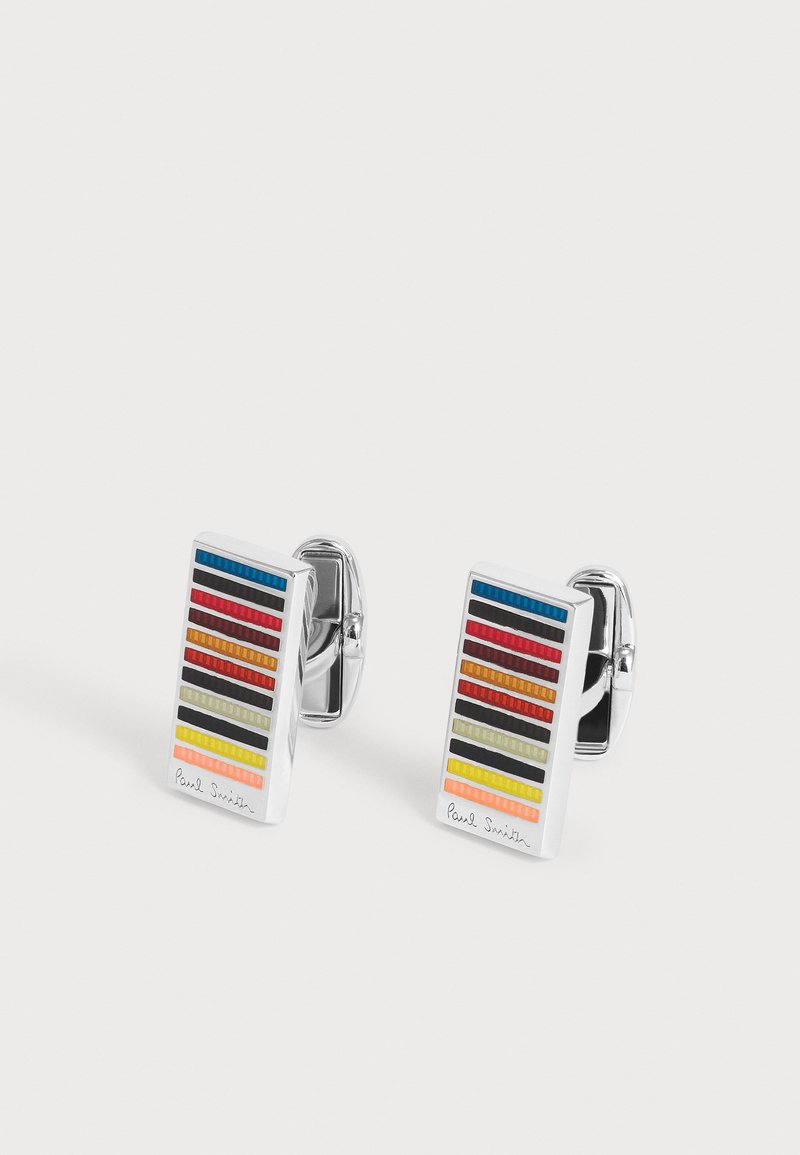 Boutons de manchette rectangulaires en argent avec des rayures multicolores horizontales et la signature "Paul Smith" en bas sur un fond blanc.