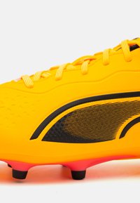 Scarpino da calcio giallo brillante con accenti neri, superficie testurizzata e strisce diagonali. Presenta tacchetti neri e tallone rinforzato.