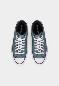 Par plave Converse All Star tenisica s bijelim vezicama i kapicama na prstima, pogled odozgo na bijeloj pozadini.