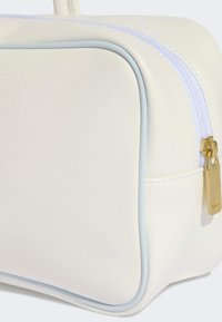 Bijela torbica od umjetne kože s plavim obrubom, zlatnim patentnim zatvaračem i glatkom teksturom. Ima pravokutni oblik i suptilne dodatke.