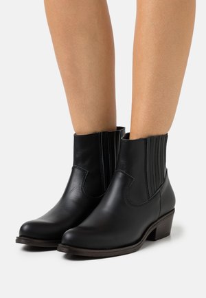 Musta nahkasaapaat nilkkamittaisilla, joustavilla sivupaneeleilla, teräväkärkisillä ja matalilla pinottuilla koroilla. Sileä pinta ja hyvin istuva muoto.